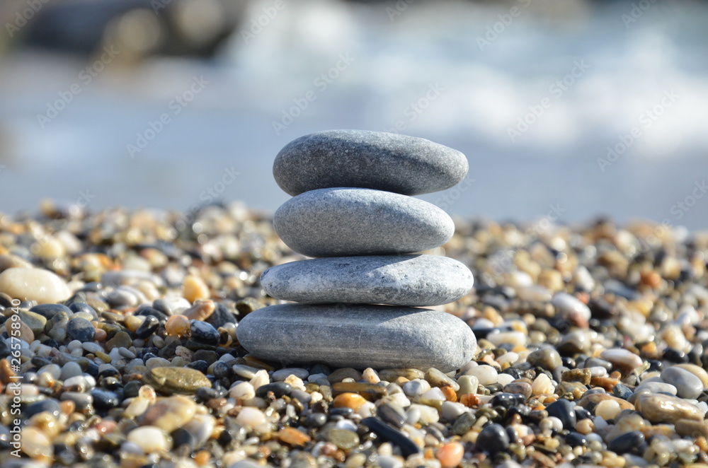 Zen pyramid of spa stones on the blurred sea background. Sand on a beach. Sea shores. Water waves texture. Place for text. concept of balance and spirituality Zen pyramid of spa stones on the blurred sea background. Sand on a beach. Sea shores. Water waves texture. Place for text. concept of balance and spirituality
