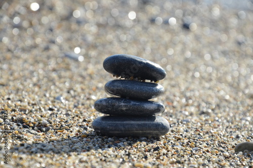 Zen pyramid of spa stones on the blurred sea background. Sand on a beach. Sea shores. Water waves texture. Place for text. concept of balance and spirituality