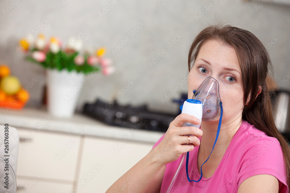 woman makes inhalation nebulizer at home. holding a mask nebulizer inhaling fumes spray the medication into your lungs sick patient. self-treatment of the respiratory tract using inhalation nebulizer woman makes inhalation nebulizer at home. holding a mask nebulizer inhaling fumes spray the medication into your lungs sick patient. self-treatment of the respiratory tract using inhalation nebulizer