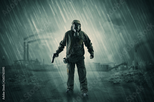 Gas masked survival man coming with arms on his hand  in a demolished dark environment 
