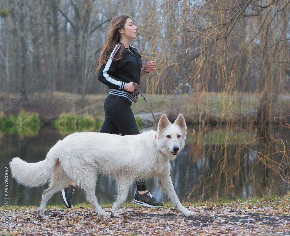Young girl with dog running at the forest