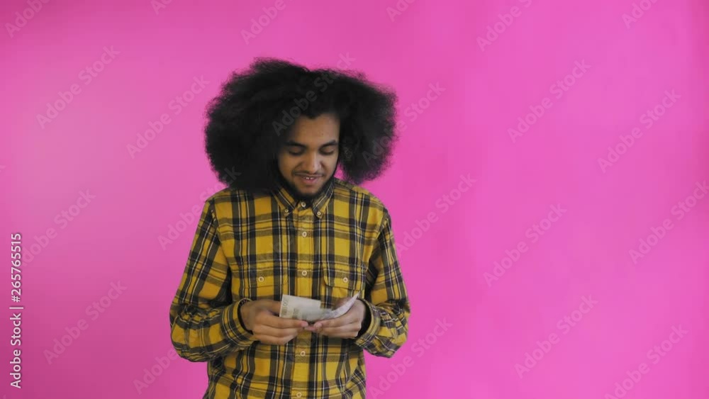Young African American man counting cash money on purple background. Young African American man counting cash money on purple background.