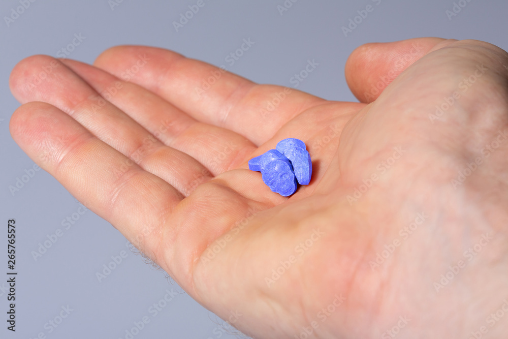 A caucasian handpalm with blue MDMA, Amphetamine, Army Skull, Ecstasy or XTC pills.