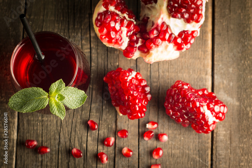 Pomegranate juice with fresh pomegranate fruits on wooden background. soft drink with lime, mint and ice.