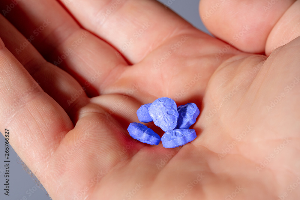 Close-up of a caucasian handpalm with blue MDMA, Amphetamine, Army Skull, Ecstasy or XTC pills. Close-up of a caucasian handpalm with blue MDMA, Amphetamine, Army Skull, Ecstasy or XTC pills.