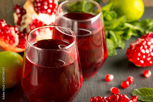 Pomegranate juice with fresh pomegranate fruits on wooden background. soft drink with lime, mint and ice.