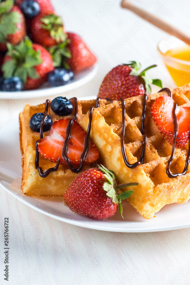 Fresh homemade food of berry Belgian waffles with honey, chocolate, strawberry, blueberry, maple syrup and cream. Healthy dessert breakfast concept with juice Fresh homemade food of berry Belgian waffles with honey, chocolate, strawberry, blueberry, maple syrup and cream. Healthy dessert breakfast concept with juice