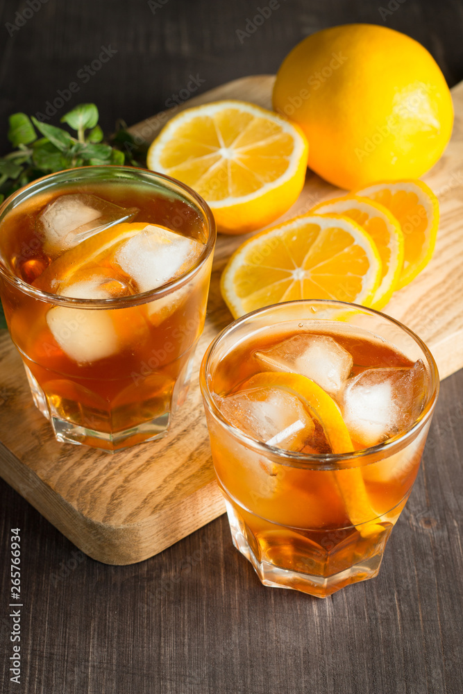 Glasses of cold ice tea with lemon, ice, mint on background. Homemade lemonade. Spring and summer drinks and beverages concept. Glasses of cold ice tea with lemon, ice, mint on background. Homemade lemonade. Spring and summer drinks and beverages concept.
