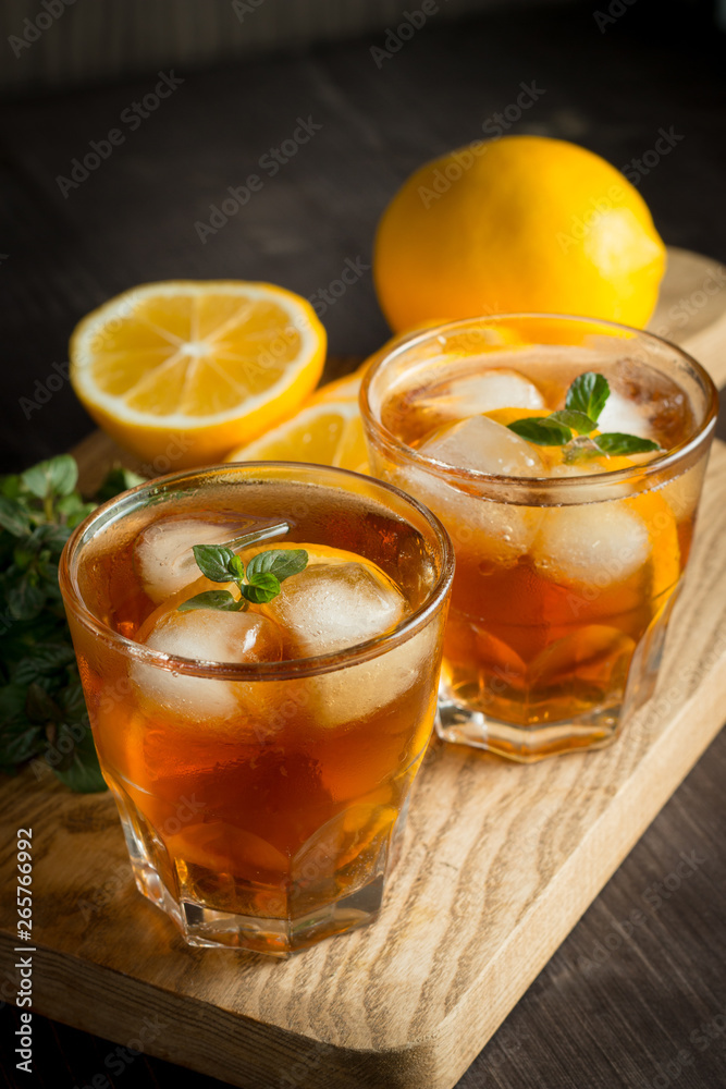 Glasses of cold ice tea with lemon, ice, mint on background. Homemade lemonade. Spring and summer drinks and beverages concept. Glasses of cold ice tea with lemon, ice, mint on background. Homemade lemonade. Spring and summer drinks and beverages concept.