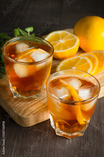 Glasses of cold ice tea with lemon, ice, mint on background. Homemade lemonade. Spring and summer drinks and beverages concept. 