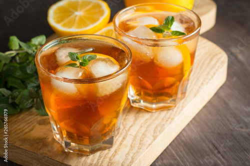 Glasses of cold ice tea with lemon, ice, mint on background. Homemade lemonade. Spring and summer drinks and beverages concept. 