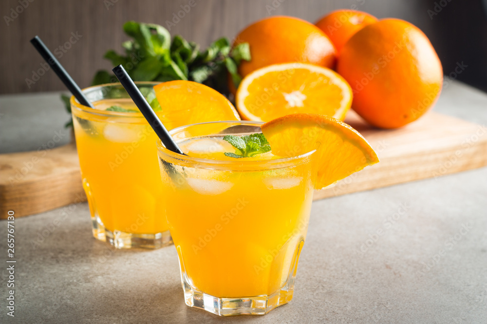 Photo of fresh orange juice in the glass jar. Summer healthy organic drink concept. Cold beverages with ice and orange fruits. Photo of fresh orange juice in the glass jar. Summer healthy organic drink concept. Cold beverages with ice and orange fruits.
