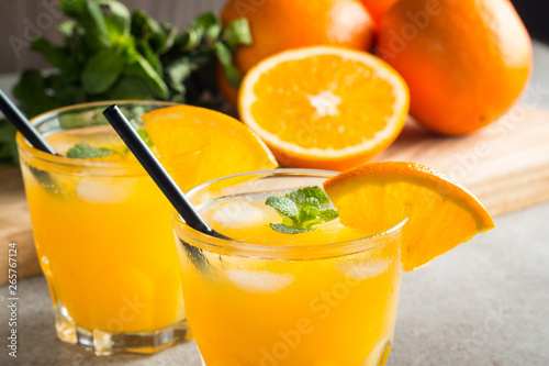 Photo of fresh orange juice in the glass jar. Summer healthy organic drink concept. Cold beverages with ice and orange fruits.