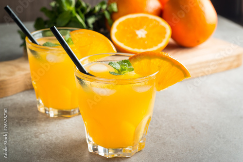 Photo of fresh orange juice in the glass jar. Summer healthy organic drink concept. Cold beverages with ice and orange fruits.