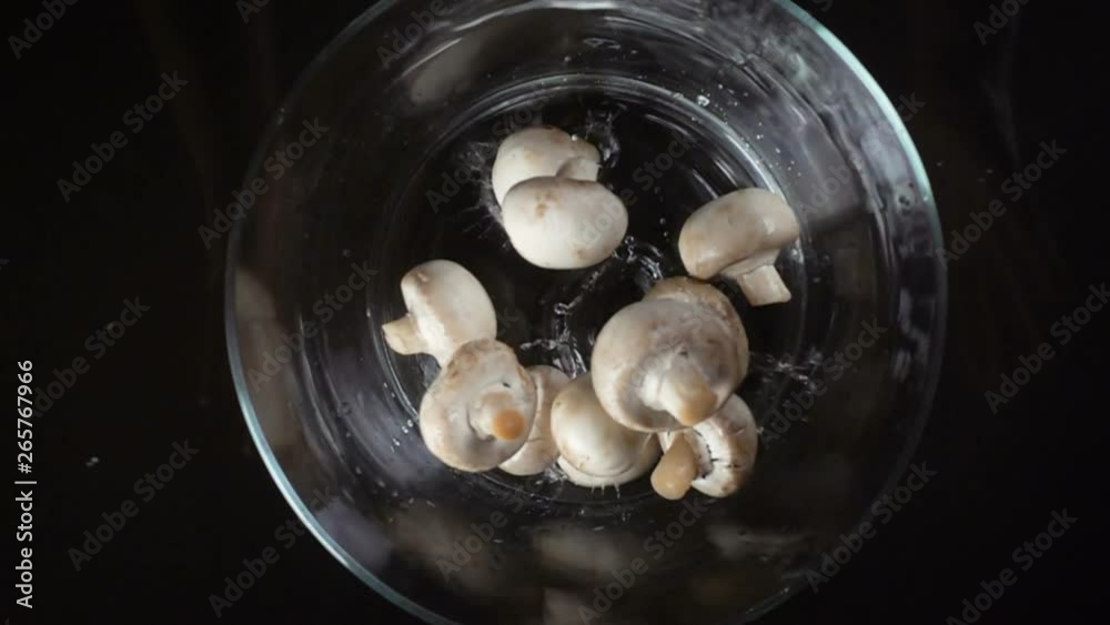 Falling white mushrooms in glass bowl, slow motion Falling white mushrooms in glass bowl, slow motion