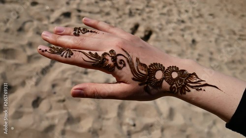 Rotating shot of henna tattooed newly done in sandy beach Persian gulf Rotating shot of an eastern girls hand newly henna tattoo done sandy beach white skin