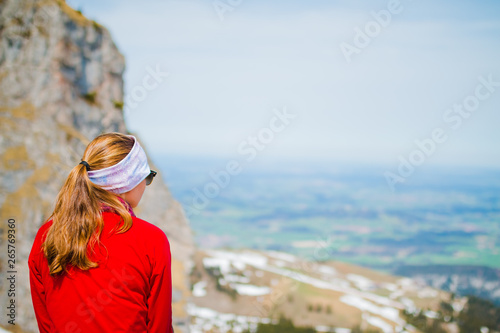 Junge Frau sitzt auf einem Berg in den Allgäuer Alpen und schaut in die Ferne des Tals