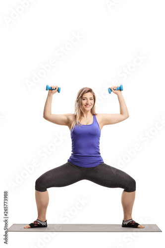 Young sporty female lifting dumbbells