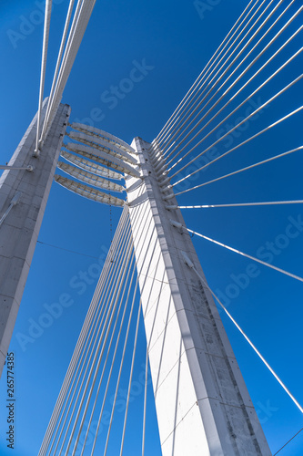 Detail of a white suspension bridge on a clear blue sky