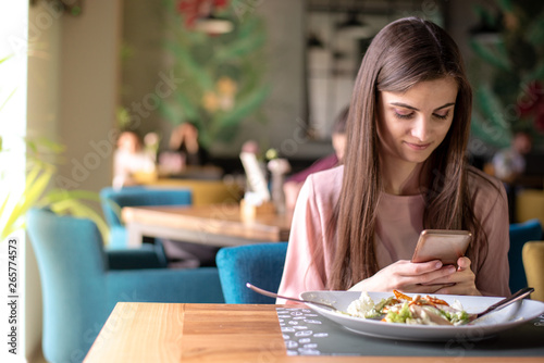 Young woman browsing internet on mobile phone at lunch
