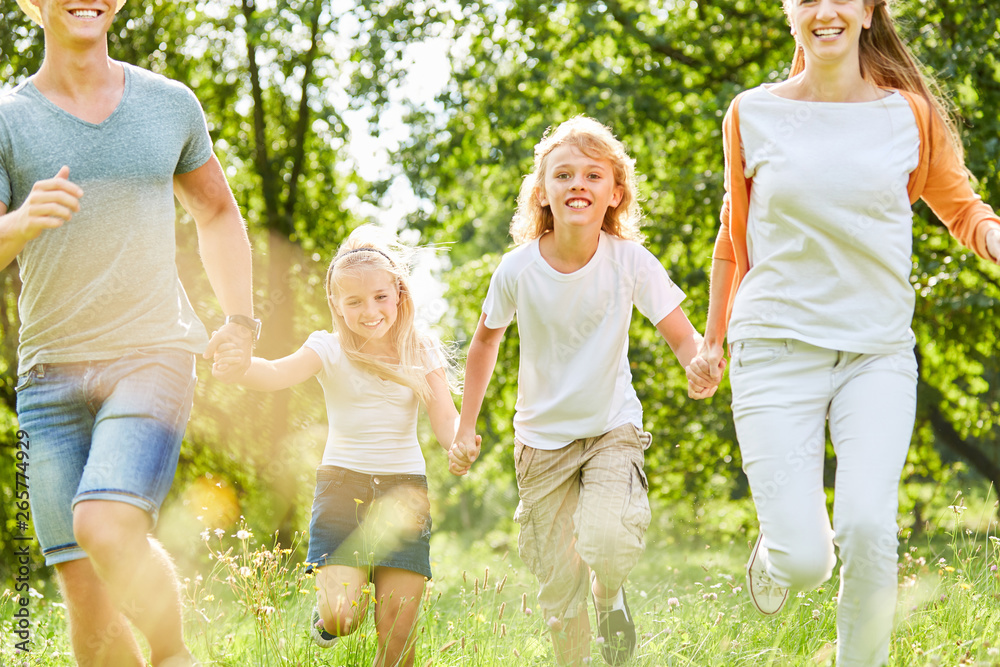 Fototapeta premium Junge läuft mit Familie über Sommer Wiese