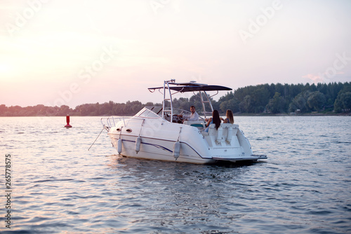 Young attractive people having good time on a boat with drinks