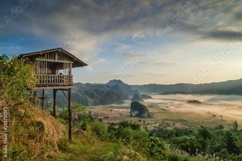 Mountain view morning of wooden house around with green forest, sea of fog with cloudy sky background, Photo Corner View Point, Route 1148 Phu Langka, Phayao, Thailand. © Yuttana Joe