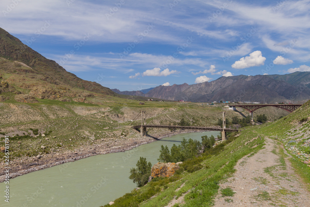 Old wooden Bridge on  iron ropes and new metal bridge through the Katun River. Summer sunny day. Long shot.