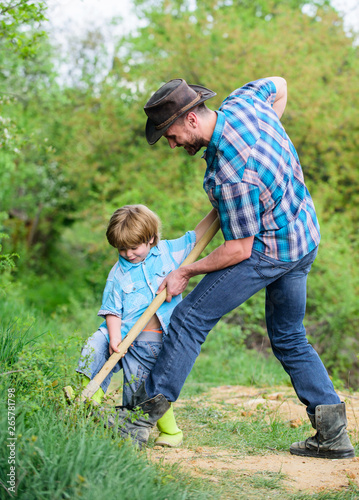 Little helper in garden. Cute child in nature having fun with cowboy dad. Find treasures. Little boy and father with shovel looking for treasures. Happy childhood. Adventure hunting for treasures