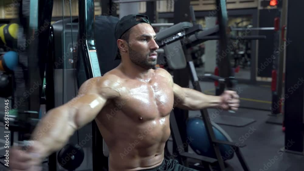 Muscular bodybuilder handsome man with a naked torso doing exercises in gym. Muscular bodybuilder handsome man with a naked torso doing exercises in gym.