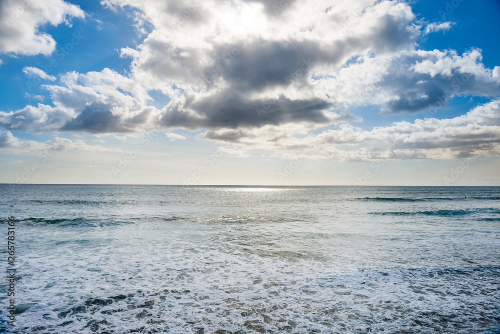 Obraz premium Seascape with silver sunlight reflection, sky and clouds