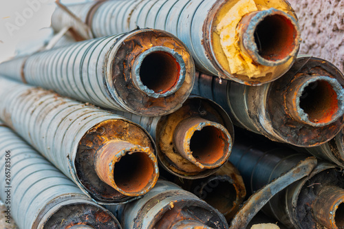 Stack of corroded steel pipes with worn insulation industrial background