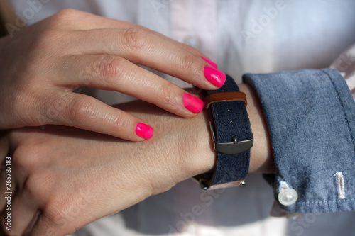 Manicured hand with pink nail and sleeve of shirt and hand watch