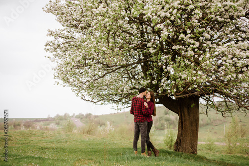 Young romantic couple walking on the meadow and blooming tree and have fun © rostyslav84
