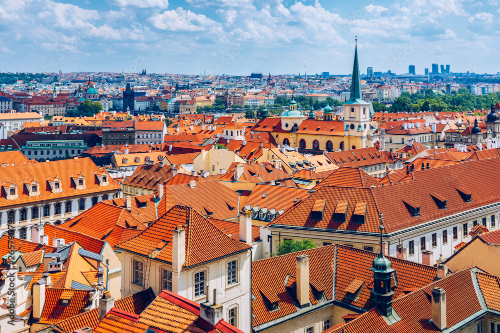 Prague red roofs and dozen spires of historical Old Town of Prague. Cityscape of Prague on a sunny day. Red rooftops, spires and the Charles Bridge and Vltava River in the background. Prague, Czechia.
