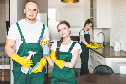 Cleaning service with professional equipment during work. professional kitchenette cleaning, sofa dry cleaning, window and floor washing. man and women in uniform, overalls and rubber gloves