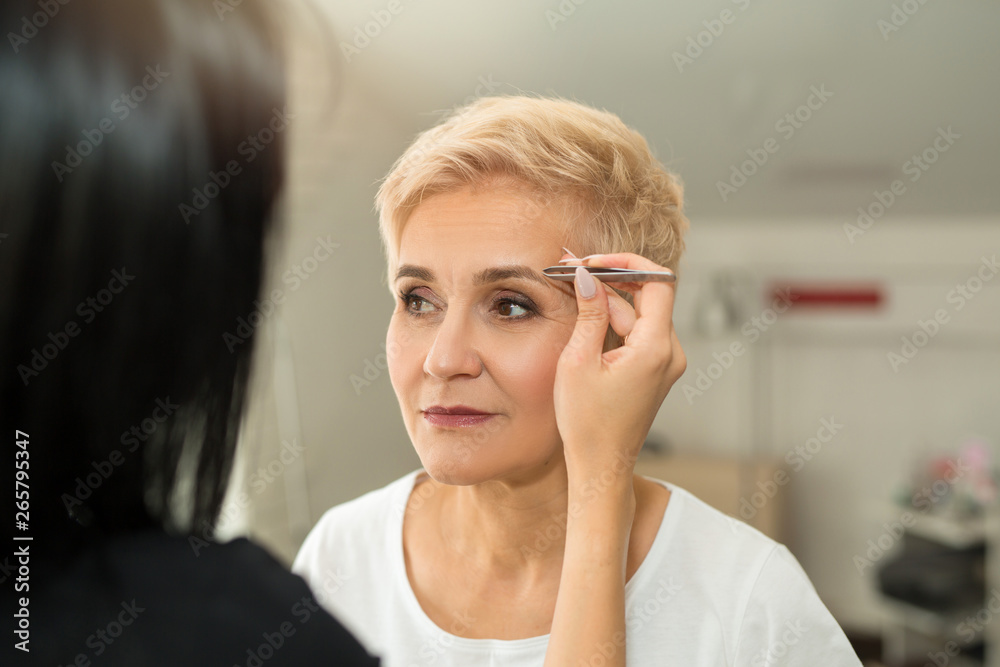 aged woman at a reception with eyebrow correction specialist aged woman at a reception with eyebrow correction specialist