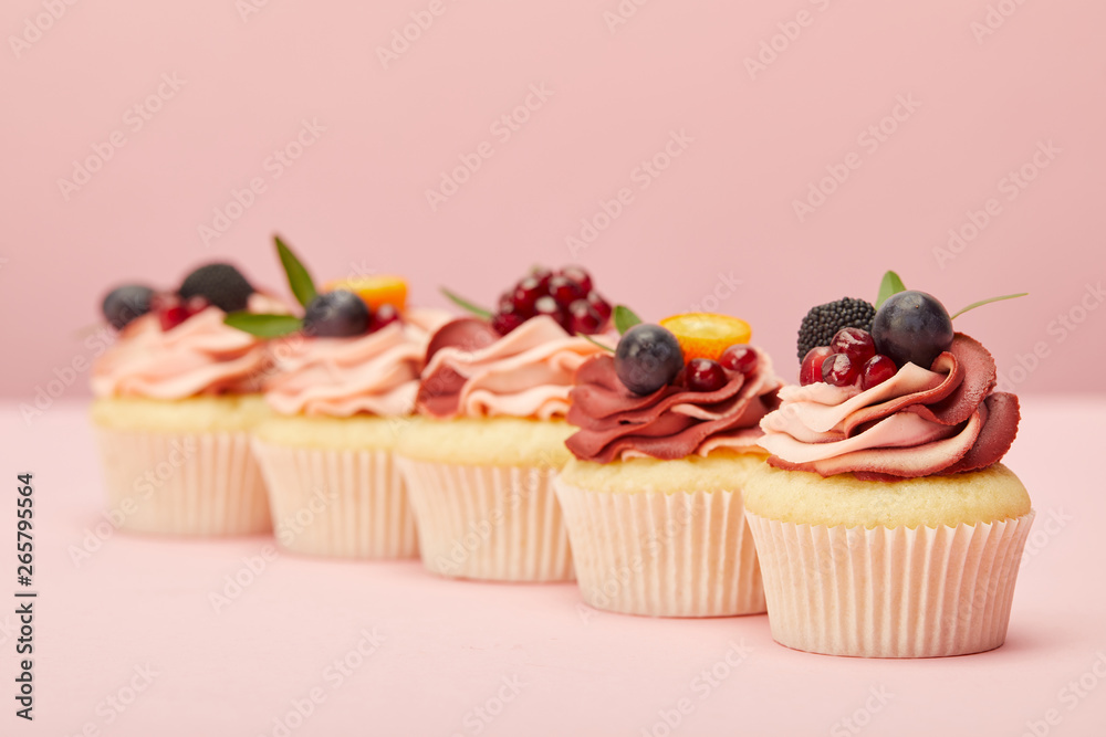 sweet cupcakes with fruits and berries on pink surface