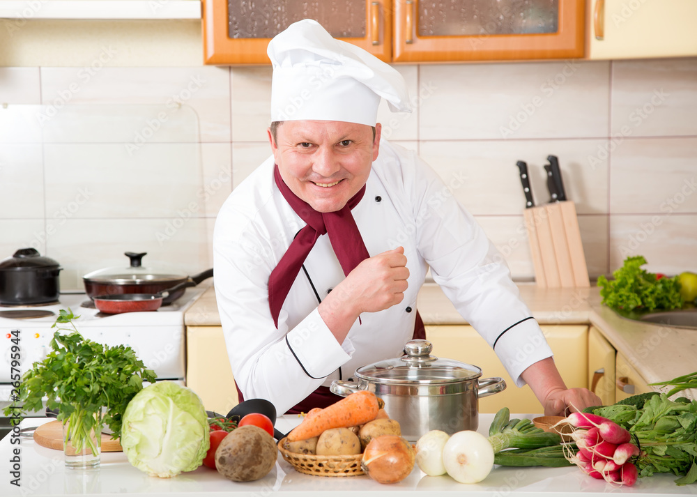 Portrait of a male cook in the kitchen. Male chef cooks food. Portrait of a male cook in the kitchen. Male chef cooks food.