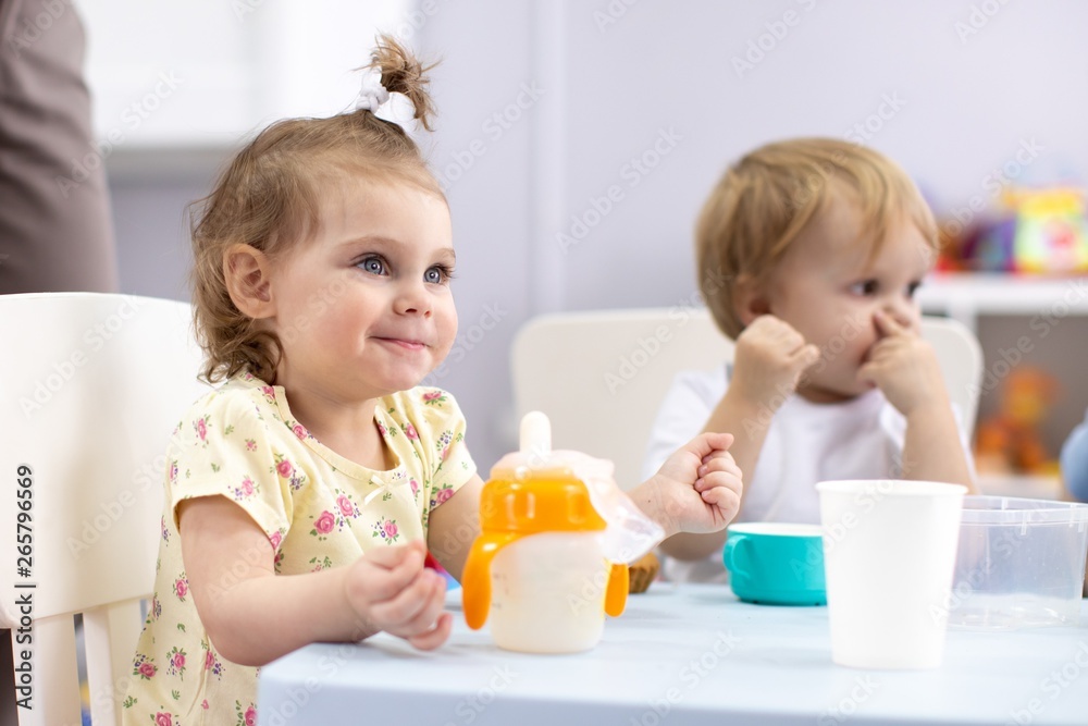 Adorable toddler girl drinking cow milk for breakfast. Healthy child having milk as health calcium source. Kid eats in nursery in the morning. Adorable toddler girl drinking cow milk for breakfast. Healthy child having milk as health calcium source. Kid eats in nursery in the morning.