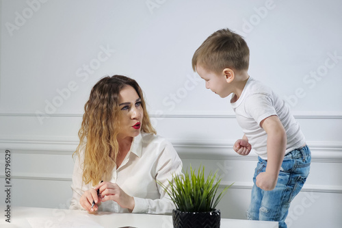 Canvas-taulu Young woman secretary with her little son in the workplace in office