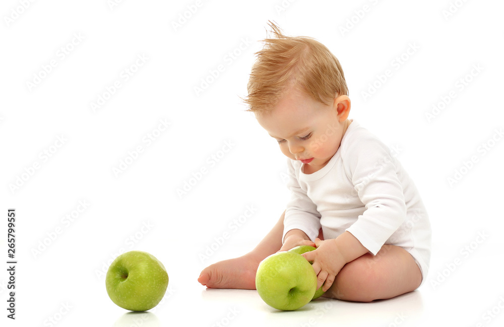 Baby 11 months old in white bodysuit sitting on white background with green apples Baby 11 months old in white bodysuit sitting on white background with green apples