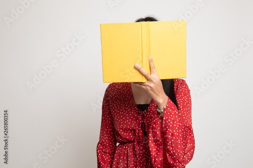 Young Asian woman with a book cover her face.