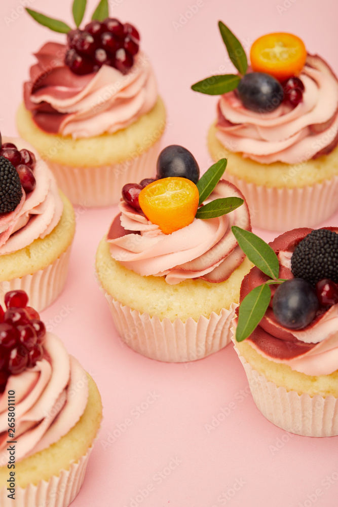 sweet cupcakes with fruits and berries on pink surface sweet cupcakes with fruits and berries on pink surface