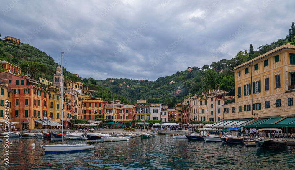 Panoramic view to Portofino in Liguria coast. Province of Genoa, Italy. Sunny summer day panorama and blue dramatic sky with clouds. Ancient european italian terracotta color houses.