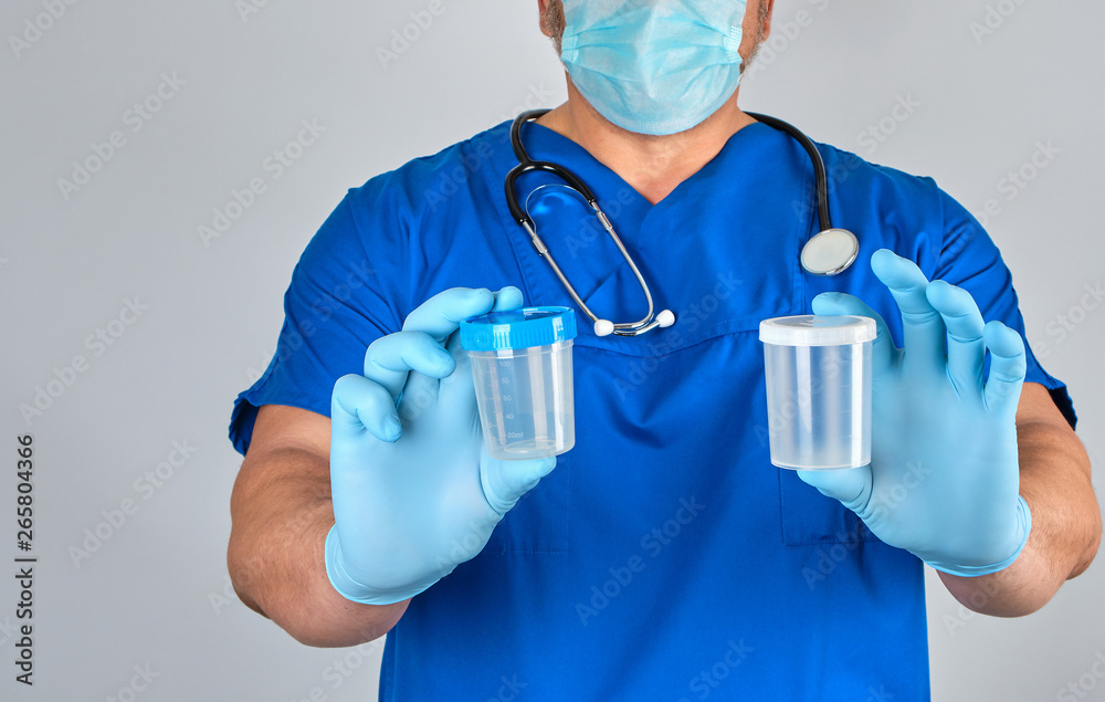 doctor in blue uniform and latex gloves is holding an empty plastic container for taking urine samples doctor in blue uniform and latex gloves is holding an empty plastic container for taking urine samples
