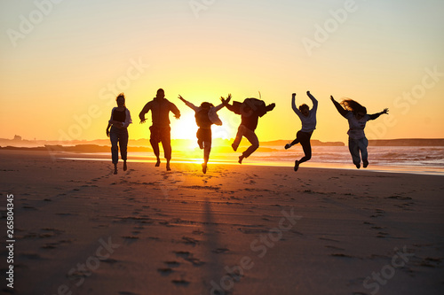 Friends jumping on a sunny beach