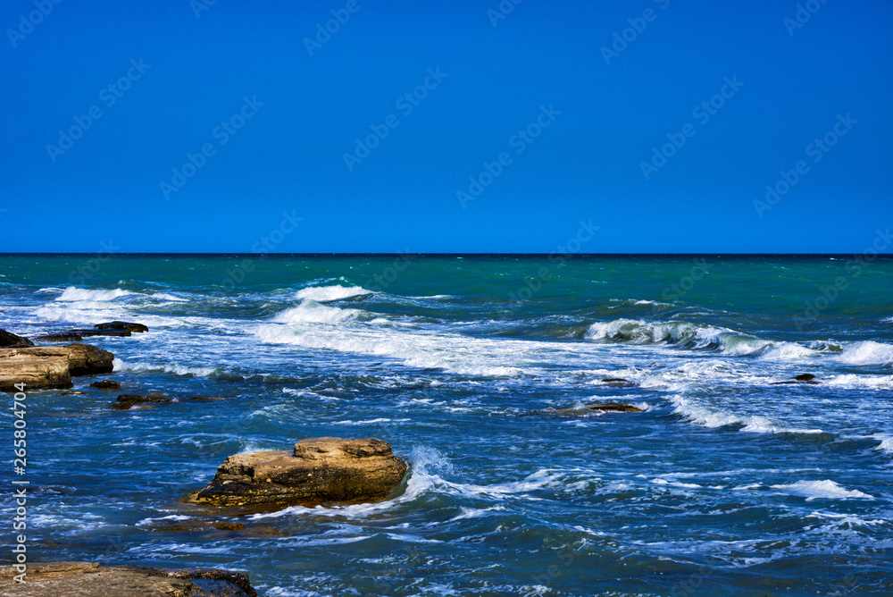 Summer landscape. Rocky coastline with a cove and rock, split view above water surface, Mediterranean sea, Spain. Azure sea, wave and blue sky. Seascape with sea horizon and clear deep blue sky.