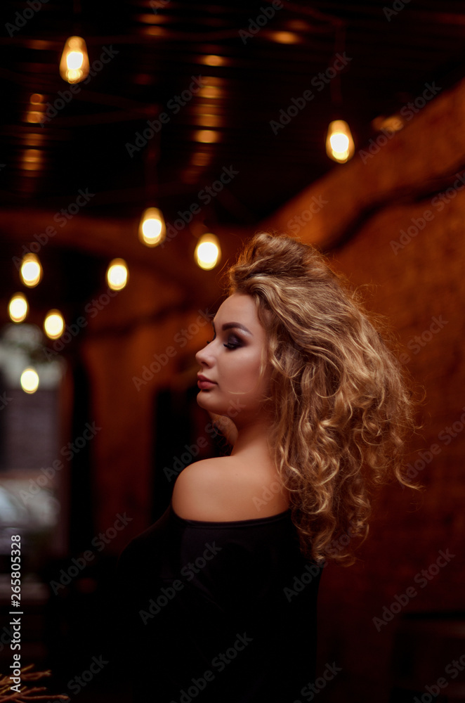  Stylish handsome  curly blonde wearing chic little black dress. Glamour girl posing and smiling at camera.