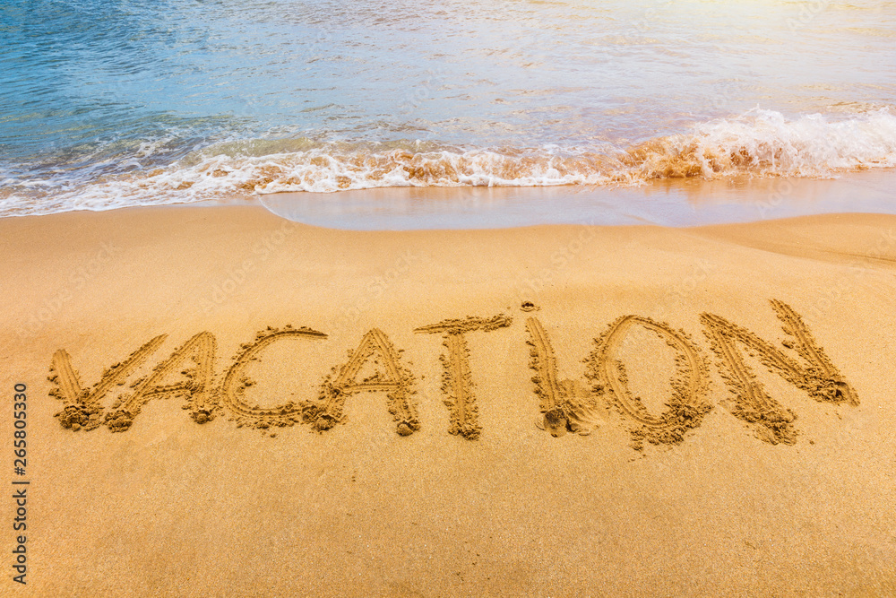 Fototapeta premium Vacation text on a beach. Vacation written in a sandy tropical beach.